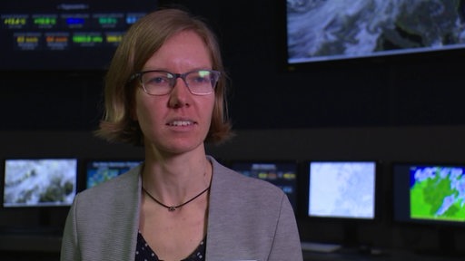 Meteorologin Annika Brieber steht in einem Raum mit Monitoren