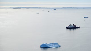 Ein Schiff fährt übers Meer mit nur wenigen Eisschollen.