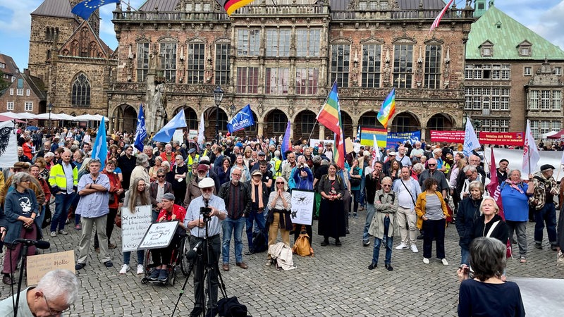 Demonstranten mit Friedensfahnen stehen auf dem Bremer Marktplatz vor dem Rathaus