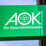 Logo der Krankenkasse AOK auf einem Schild