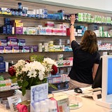 Eine Mitarbeiterin einer Apotheke greift nach freiverkäuflichen Arzneimitteln.
