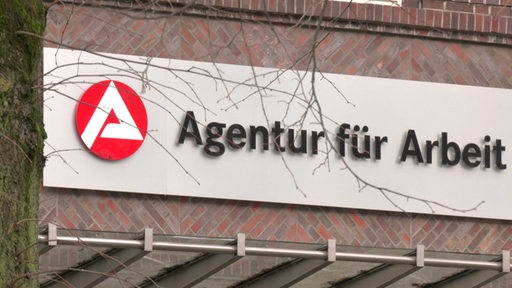 An einer Hauswand hängt das Schild der Agentur für Arbeit.