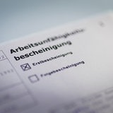 Eine Erstbescheinigung der Arbeitsunfähigkeitsbescheinigung liegt auf einem Tisch.