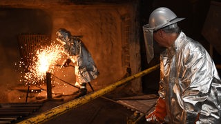 Stahlarbeiter arbeiten im Bremer Stahlwerk und Funken sprühen.