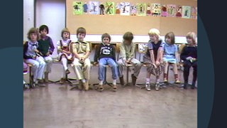 Ein Archivbild aus dem Jahr 1981. Kinder sitzen in einer Reihe nebeneinander in einem Klassenzimmer.