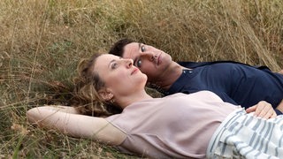 Eine Frau und ein Mann liegen im Gras - Filmszene "Ich bin dein Mensch"