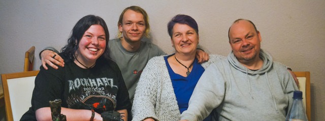 Vier Menschen, Familie Lorenz, sitzt an ihrem Esstisch und schaut in die Kamera.