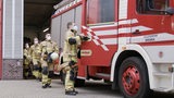 Eine Gruppe Feuerwehrmänner in voller Montur rennt zu einem Feuerwehrauto der Freiwilligen Feuerwehr Neustadt.