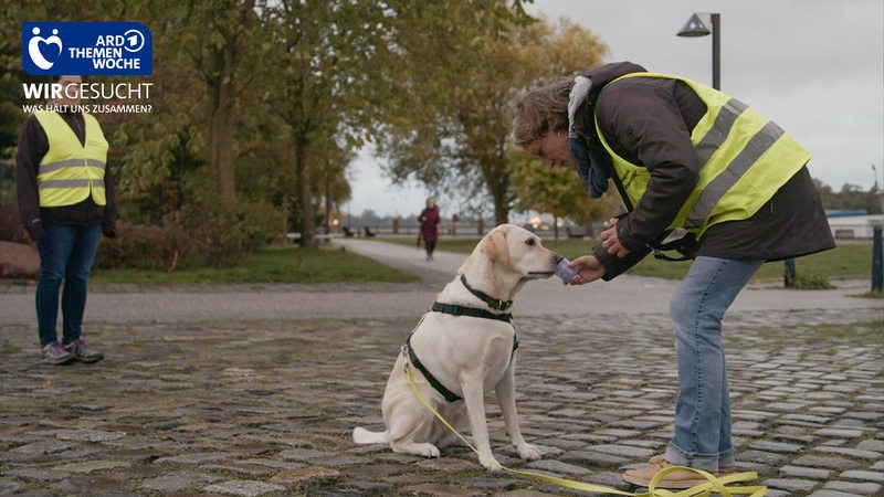 Eine Frau in Vegesack hält einem Hund einen Becher vor die Nase um ihm beizubringen, Menschen zu suchen.
