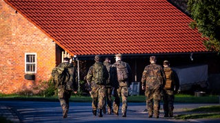 Einsatzkräfte der Bundeswehr laufen durch den Wohnort des vermissten Jungen. 