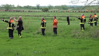 Einsatzkräfte stehen nebeneinander auf einer Wiese