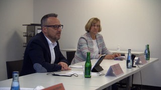 Heiko Strohmann und Sigrid Grönert sitzen auf einer Pressekonferenz nebeneinander.