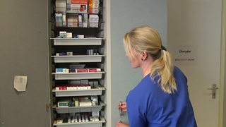 Krankenschwester öffnet einen Schrank mit Medikamenten