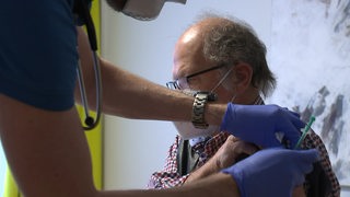 Ein älterer Mann wird in einer Hausarztpraxis geimpft.