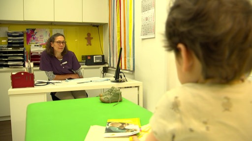Ein Kind ist einem Behandlungszimmer von einer Ärztin