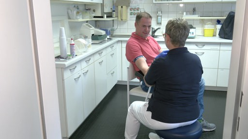 In einem Untersuchungszimmer beim Arzt, bandelt eine Ärztin einen Patient. 