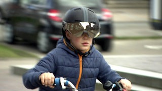 Ein Kind fährt auf dem Fahrrad und trägt einen technologischen Fahrradhelm.