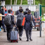 Flüchtlinge mit Gepäck am Eingang zu einem Ankunftszentrum in Niedersachsen.