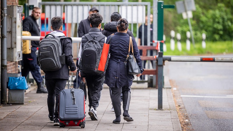 Flüchtlinge mit Gepäck am Eingang zu einem Ankunftszentrum in Niedersachsen.