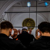 Rückenansicht junger Männer, die in einer Moschee beten