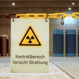 Castorbehaelter im Brennelemente - im Vordergrund ein Schild mit der Aufschrift "Kontrollbereich Vorsicht Strahlung"