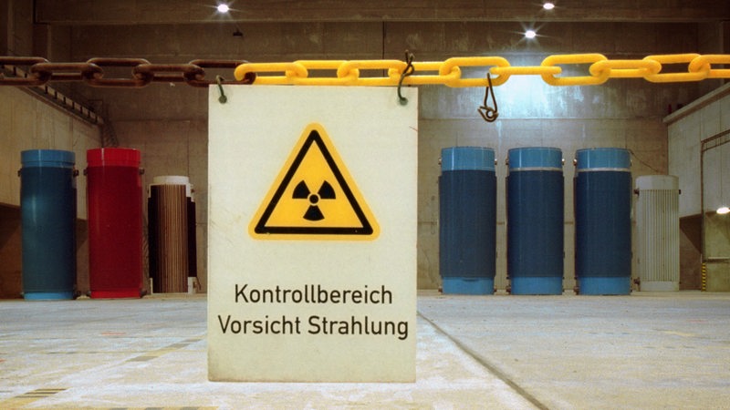 Castorbehaelter im Brennelemente - im Vordergrund ein Schild mit der Aufschrift "Kontrollbereich Vorsicht Strahlung"