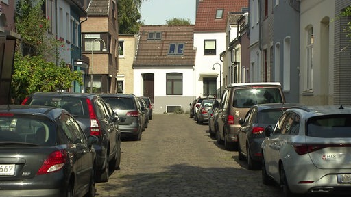 Eine Straße in Bremen, wo mehrere Autos aufgesetzt parken. 