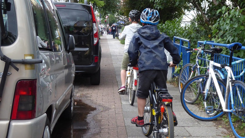 Aufgesetztes Parken in Bremen am Sielwall. Zwei fahrradfahrende Kinder haben wenig Platz, um an den Autos vorbeizukommen.