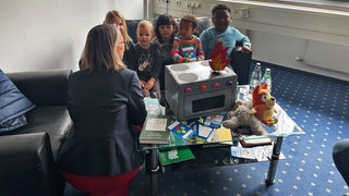 Bildungssenatorin Sascha Aulepp sitzt mit Kindergartenkindern zusammen.