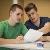 Zwei junge Männer lesen ein Papier.