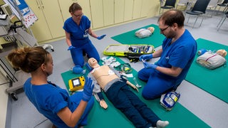 Angehende Krankenpfleger und Mediziner trainieren an einer Puppe eine Notfallversorgung