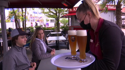 Eine Kellnerin bedient in der Bremerhavener Außengastronomie einen Tisch.