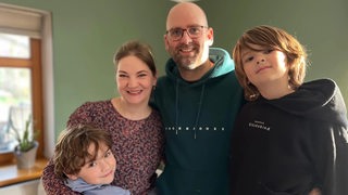 Mutter und Vater mit zwei jungen Söhnen schauen in die Kamera