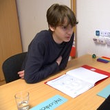Ein Junge sitzt an einem Schreibtisch.