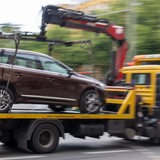 Ein Abschleppwagen mit einem Volvo fährt über eine Straße.