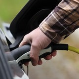 Eine Hand hält ein Aufladekabel für ein Auto