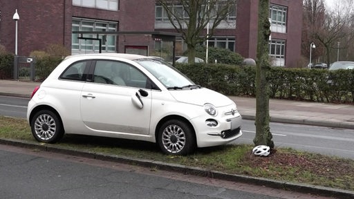 Ein Auto vor einem Baum, unten liegt ein Helm