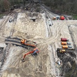 Mehrere Baustellenfahrzeuge stehen auf einer Sandfläche.