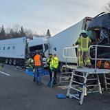 Polizisten und Feuerwehrleute sichern nach einem Unfall, bei dem mehrere Lkw aufeinander aufgefahren sind, die Unfallstelle ab.