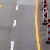 Ein Auto fährt über eine verengte Fahrbahn in einer Baustelle auf einer Autobahn.