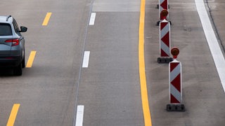 Ein Auto fährt über eine verengte Fahrbahn in einer Baustelle auf einer Autobahn.