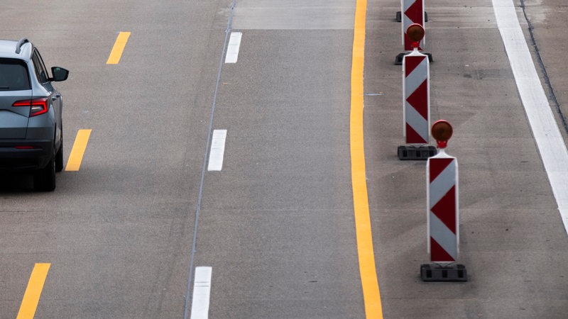 Ein Auto fährt über eine verengte Fahrbahn in einer Baustelle auf einer Autobahn.