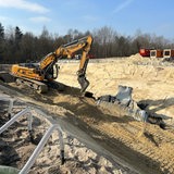 Ein Bagger ssteht in einer Sandgrube und arbeitet an einer beschädigten Röhre.