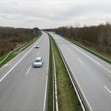 Zwei Autos fahren auf einer ansonsten leeren Autobahn.