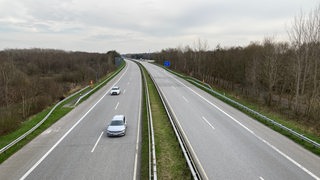 Zwei Autos fahren auf einer ansonsten leeren Autobahn.