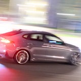 Ein getuntes Auto fährt bei Dunkelheit auf einer Straße vorbei