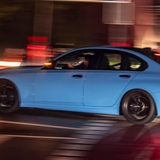 Ein getunte blaue Limousine fährt bei Dunkelheit schnell durch eine Straße bei Dunkelheit (Symbolbild)