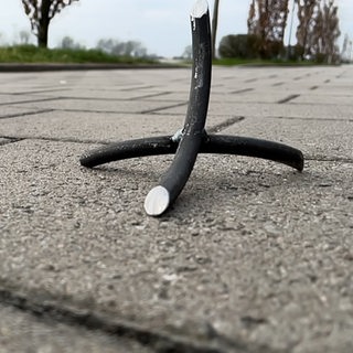Ein spitzes Metallteil liegt auf der Straße.