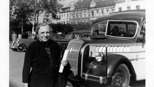 Eine Frau steht neben einem historischen Auto