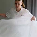 Eine Frau bezieht ein Hotelbett.